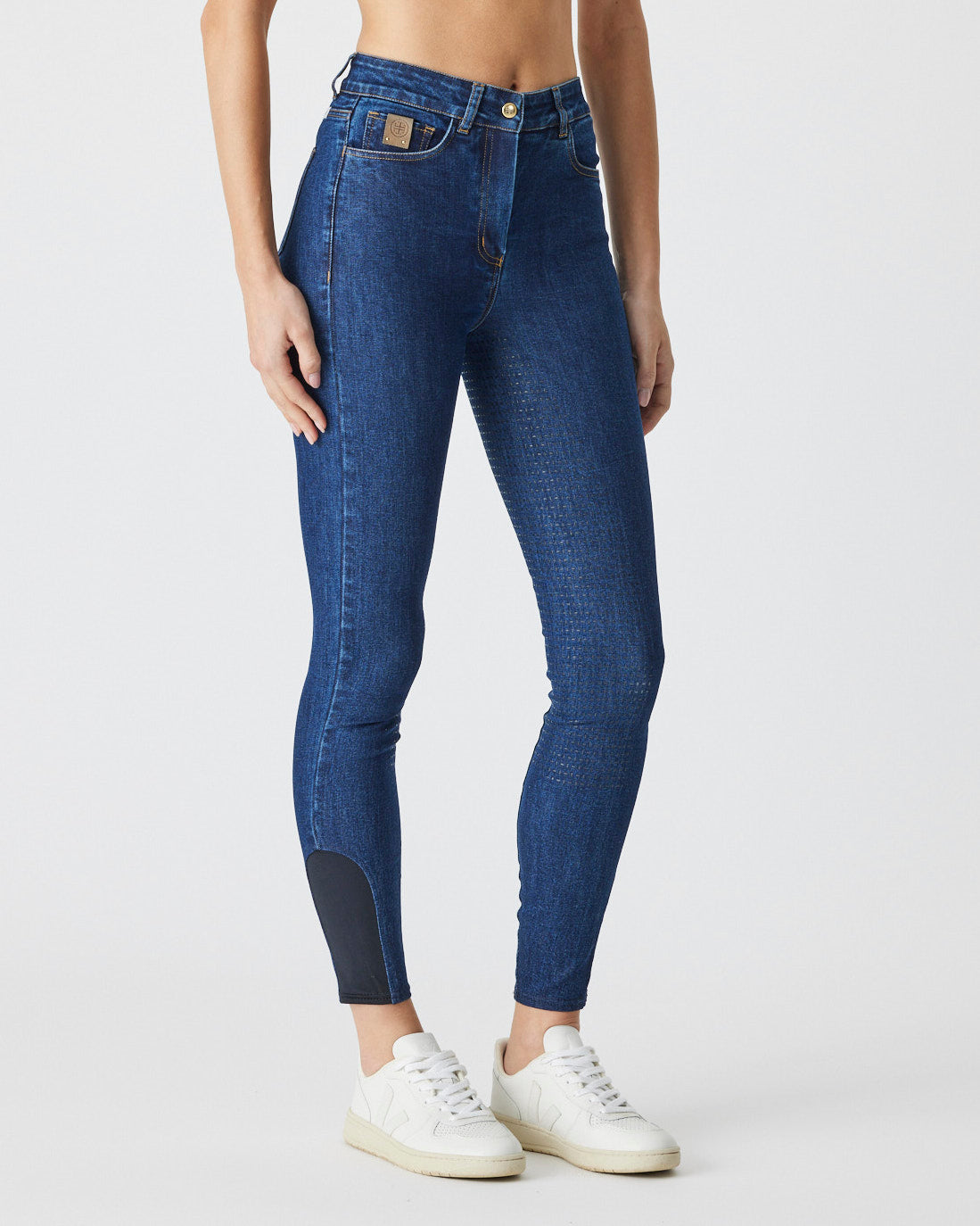 A woman wearing high waisted blue denim breeches.
